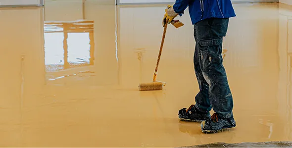 Worker with squeegee smoothing out epoxy flooring solution.