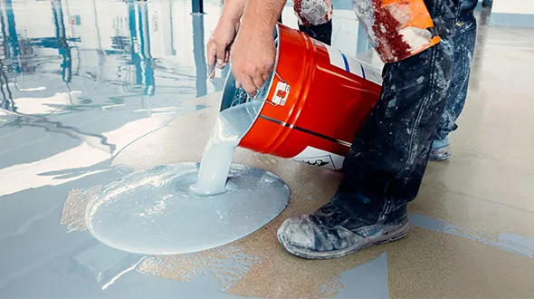 Applicator pouring epoxy for commercial flooring in Aurora, Colorado.